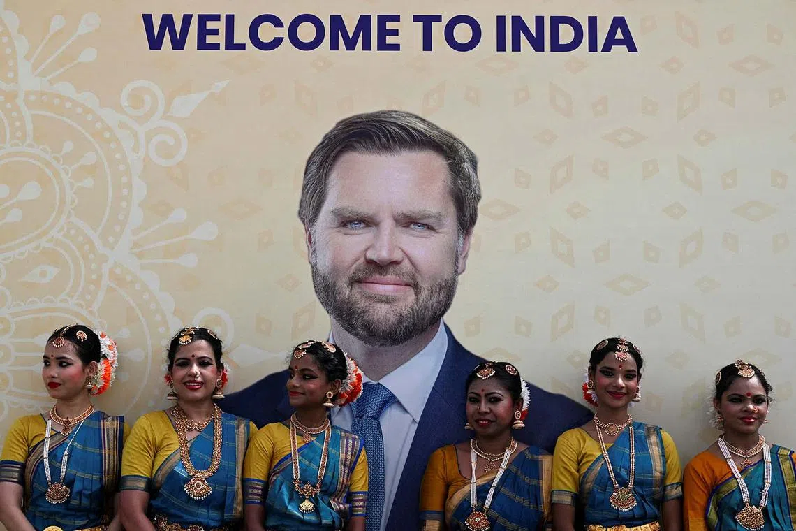 Performers standing next to a poster welcoming US Vice President JD Vance to India, in New Delhi, India, April 21, 2025. 
