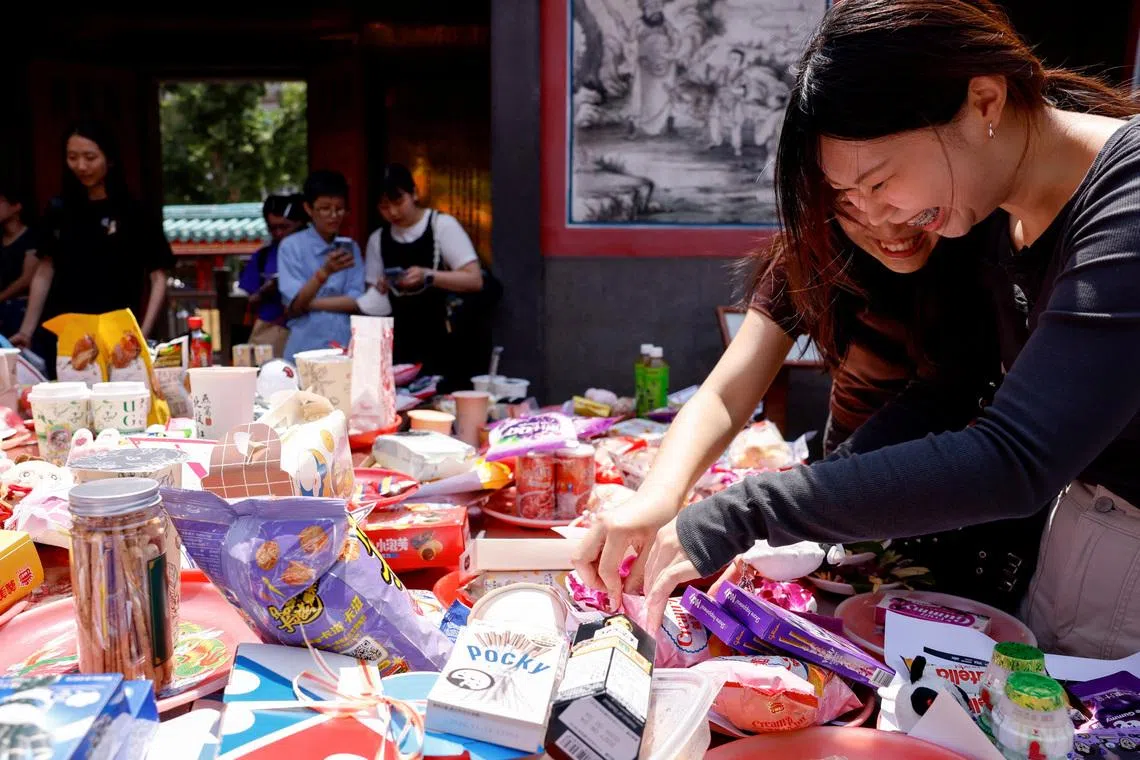 BTS fans prepare snacks, group merchandise, concert seat maps and wishlists on an altar table as they pray to Yue Lao in hopes of securing a concert ticket.