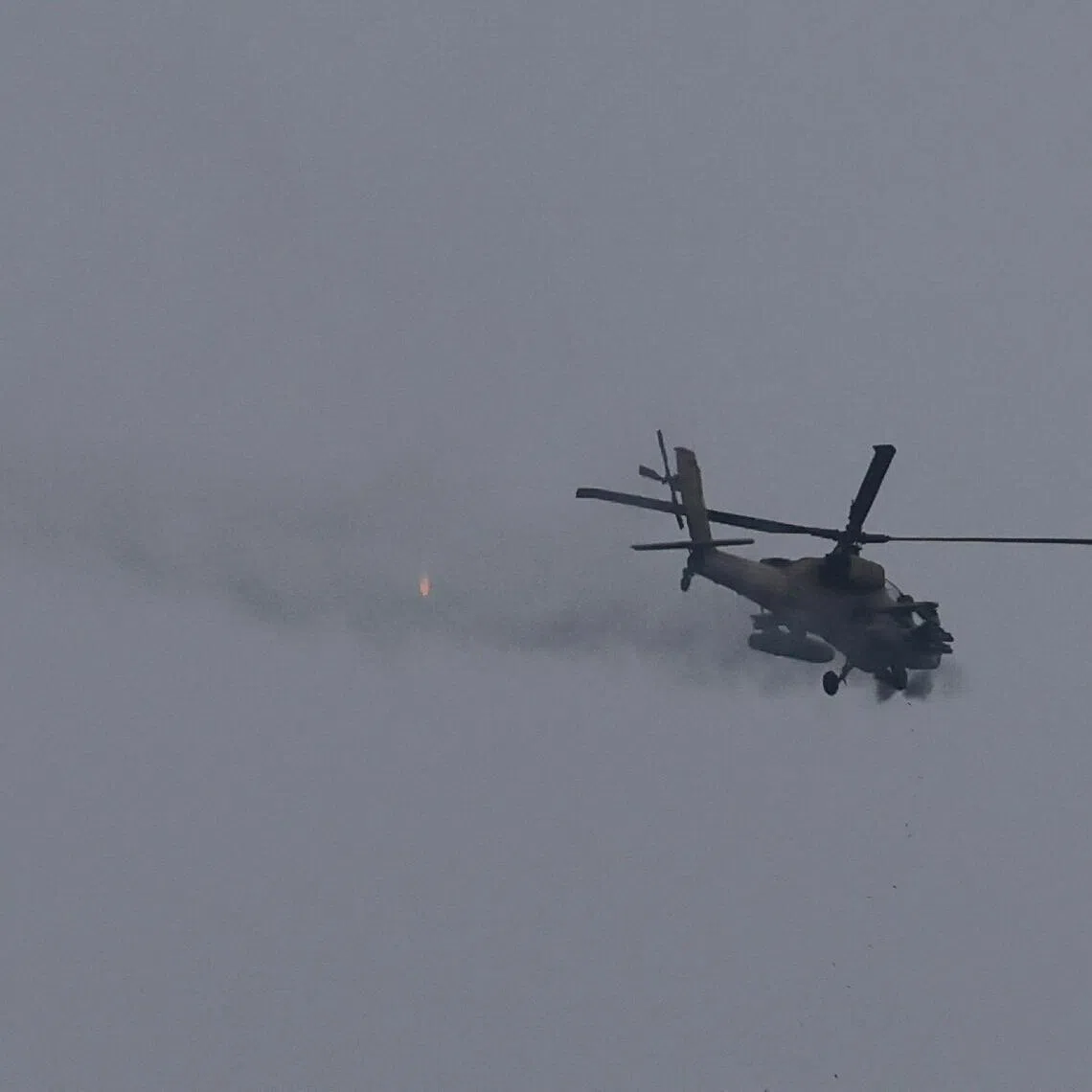 An Israeli helicopter fires its cannon, as seen from near the Israel-Lebanon border, in Israel, on May 5.
