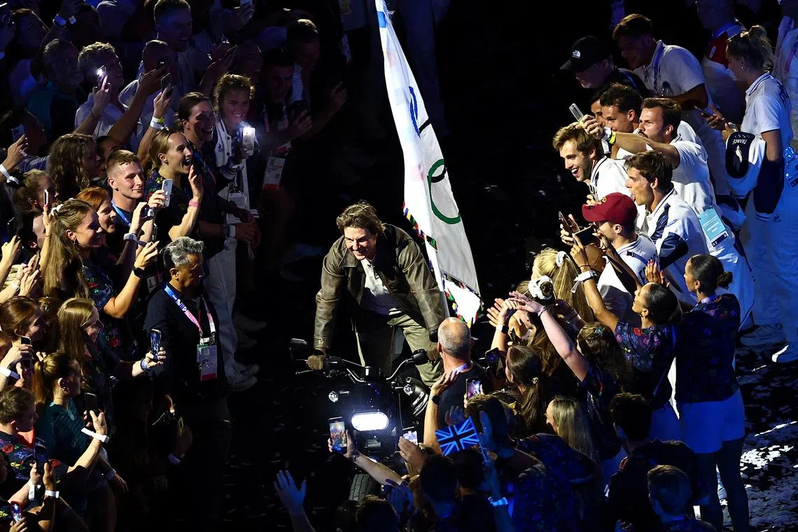 Actor Tom Cruise riding a motorbike with the Olympics flag during the closing ceremony of the Paris Olympics at the Stade de France on Aug 11, 2024.