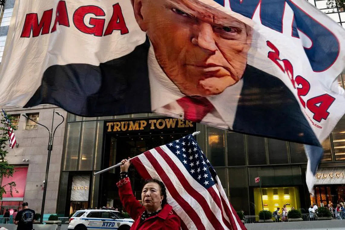 A supporter of former U.S. President Donald Trump holds up a U.S. national flag at Trump Tower in New York City, U.S., October 1, 2023. REUTERS/David 'Dee' Delgado/File Photo