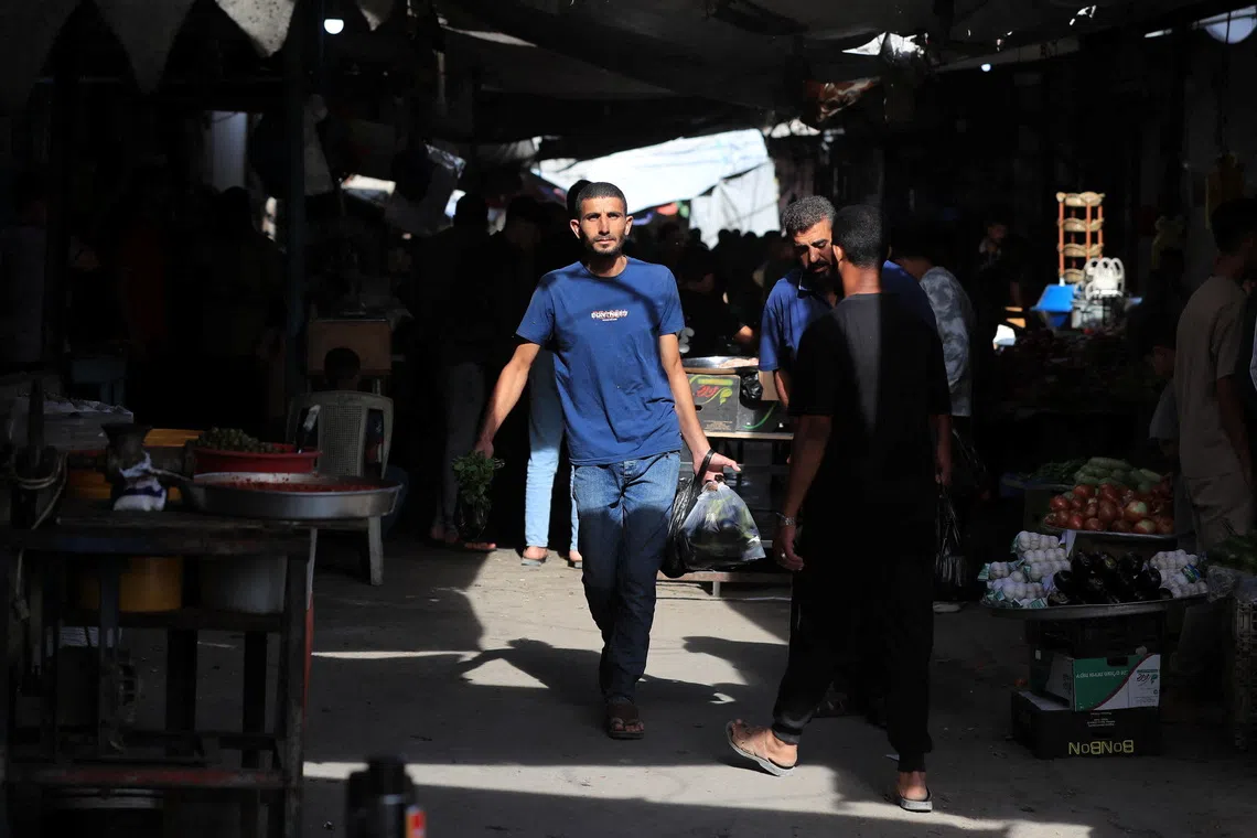 Palestinians walk through a street market in Gaza City, October 16, 2026. REUTERS/Dawoud Abu Alkas