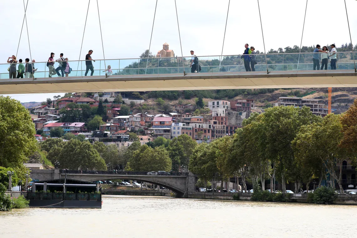 FILE PHOTO: People walk across the Bridge of Peace over the Mtkvari river in Tbilisi, Georgia September 10, 2025. REUTERS/Irakli Gedenidze/File Photo