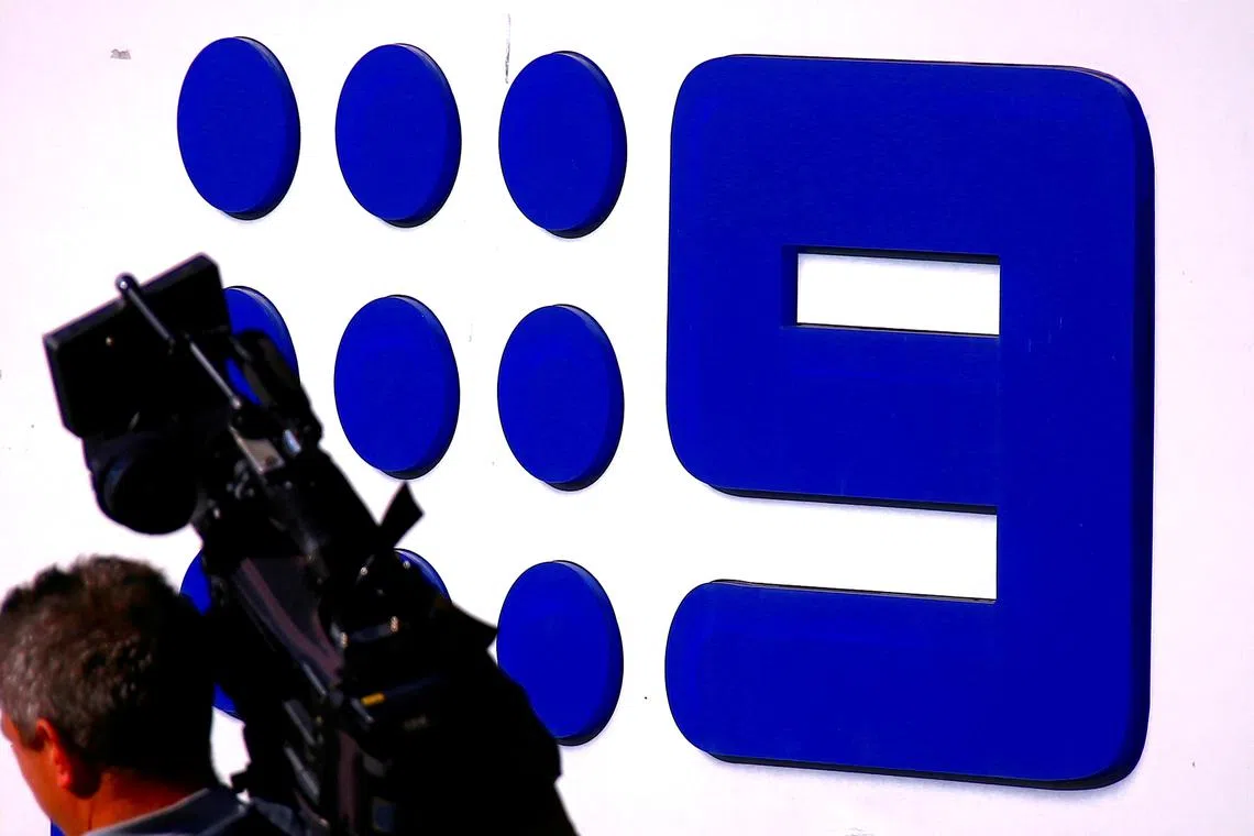 FILE PHOTO: A television cameraman walks in front of the logo of Nine Entertainment Co Holdings Ltd on display outside their Sydney headquarters in Australia, July 26, 2018.   REUTERS/David Gray/File Photo