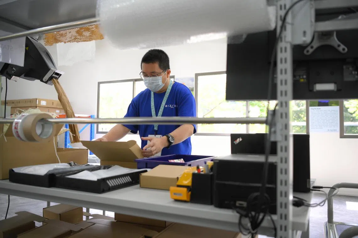 Bizlink Centre Singapore trainee Chan Yong Shen, 38, demonstrates the parcel packing process at the E-commerce Fulfilment Training Centre during the opening of the Enabling Business Hub (EBH) on December 13, 2023.
