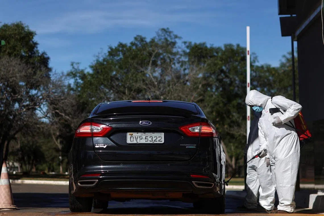 A person wearing a hazmat suit disinfects a car at the entrance to the park, after a confirmed outbreak of bird flu found in two birds in the Zoo, in Brasilia, Brazil June 4, 2025. REUTERS/Adriano Machado