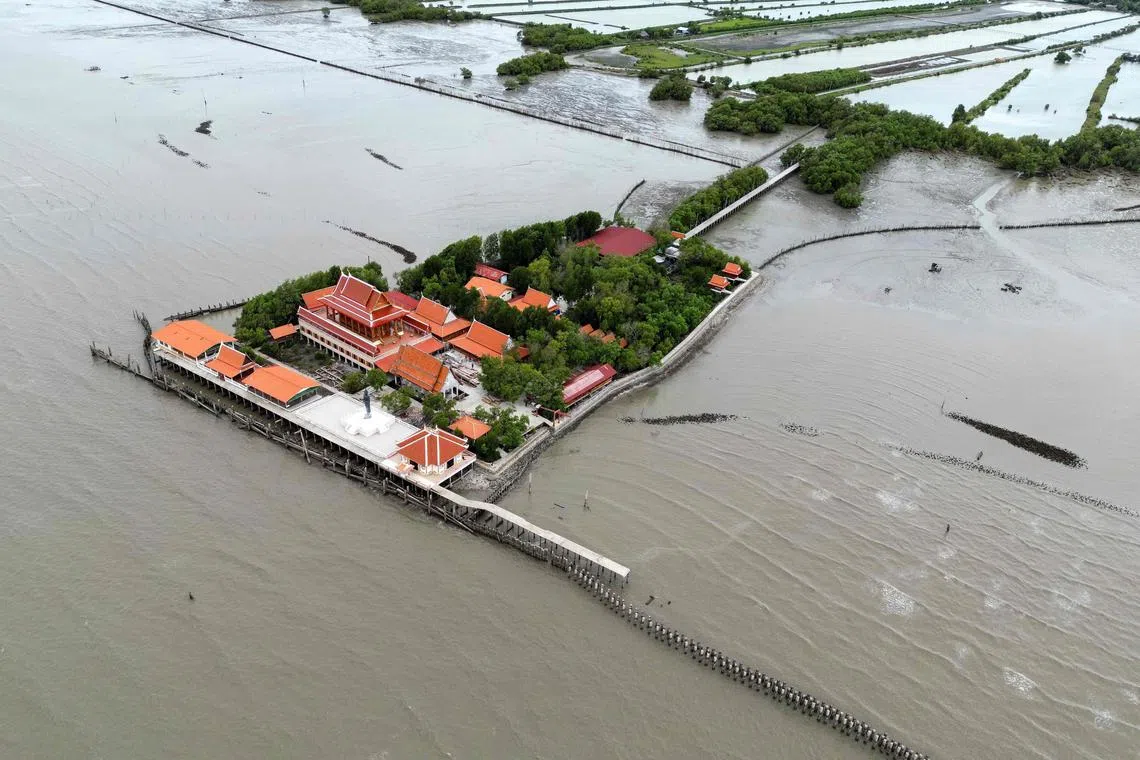 This aerial photograph taken on June 14, 2023 shows a temple surrounded by the sea in the Ban Khun Samut Chin, a coastal village less than 10km from the edge of Bangkok. Each morning, four children stand barefoot in a line and proudly sing the national anthem as the Thai flag is raised outside their school, perched on a finger of land surrounded by the sea. They are the last pupils left at the school in Ban Khun Samut Chin, a coastal village that is slowly being devoured by the waves. (Photo by Manan VATSYAYANA / AFP) / To go with Thailand-climate-environment-oceans, FOCUS by Lisa Martin and Pitcha Dangprasith