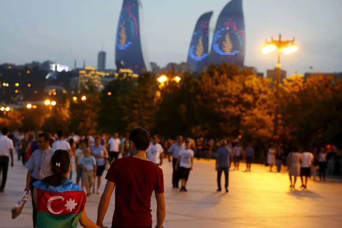 A girl, draped in Azerbaijan's national flag, walks with a boy on a street in downtown Baku, Azerbaijan June 18, 2015.  REUTERS/Stoyan Nenov/File Photo