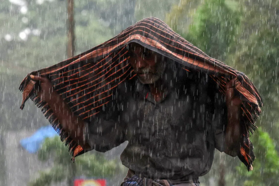 A man using his scarf to protect himself from the rain in the aftermath of Cyclone Ditwah, in Chennai, India, Dec 1, 2025.