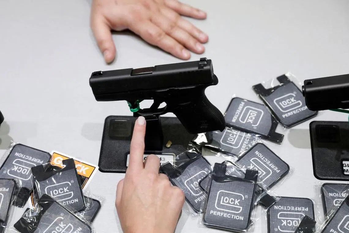 FILE PHOTO: A woman points at a Glock handgun during the annual National Rifle Association (NRA) convention in Dallas, Texas, U.S., May 6, 2018. REUTERS/Lucas Jackson/File Photo