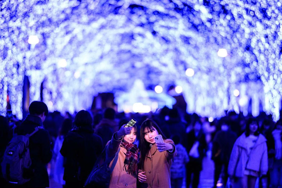 TOPSHOT - People take pictures with festive light installations, ahead of the Christmas season in Tokyo's Shibuya district on December 21, 2023. (Photo by Philip FONG / AFP)