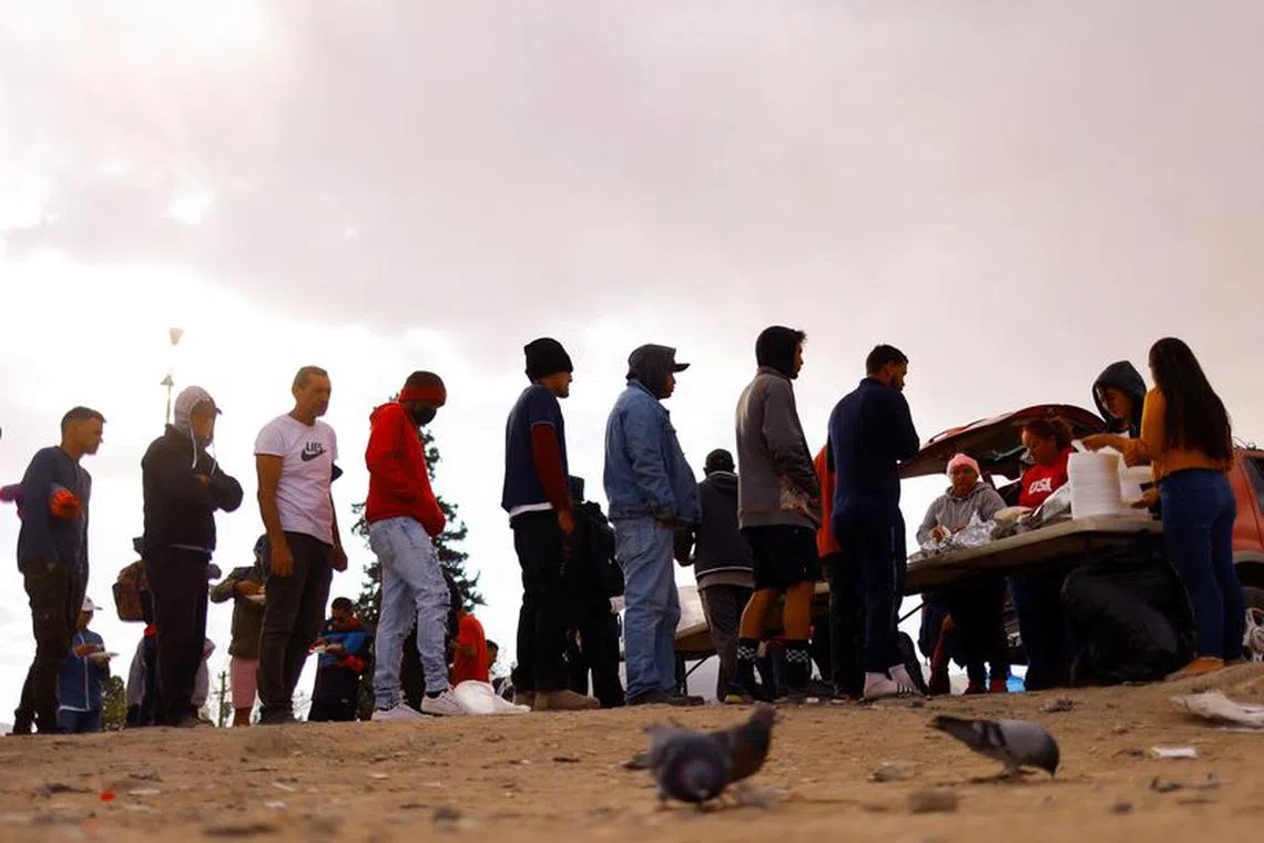 Venezuelan migrants, some expelled from the U.S. to Mexico under Title 42 and others who have not yet crossed border after the new immigration policies, queue for Thanksgiving Day food at a camp on the banks of the Rio Bravo river in Ciudad Juarez, Mexico November 24, 2022. REUTERS/Jose Luis Gonzalez/File Photo
