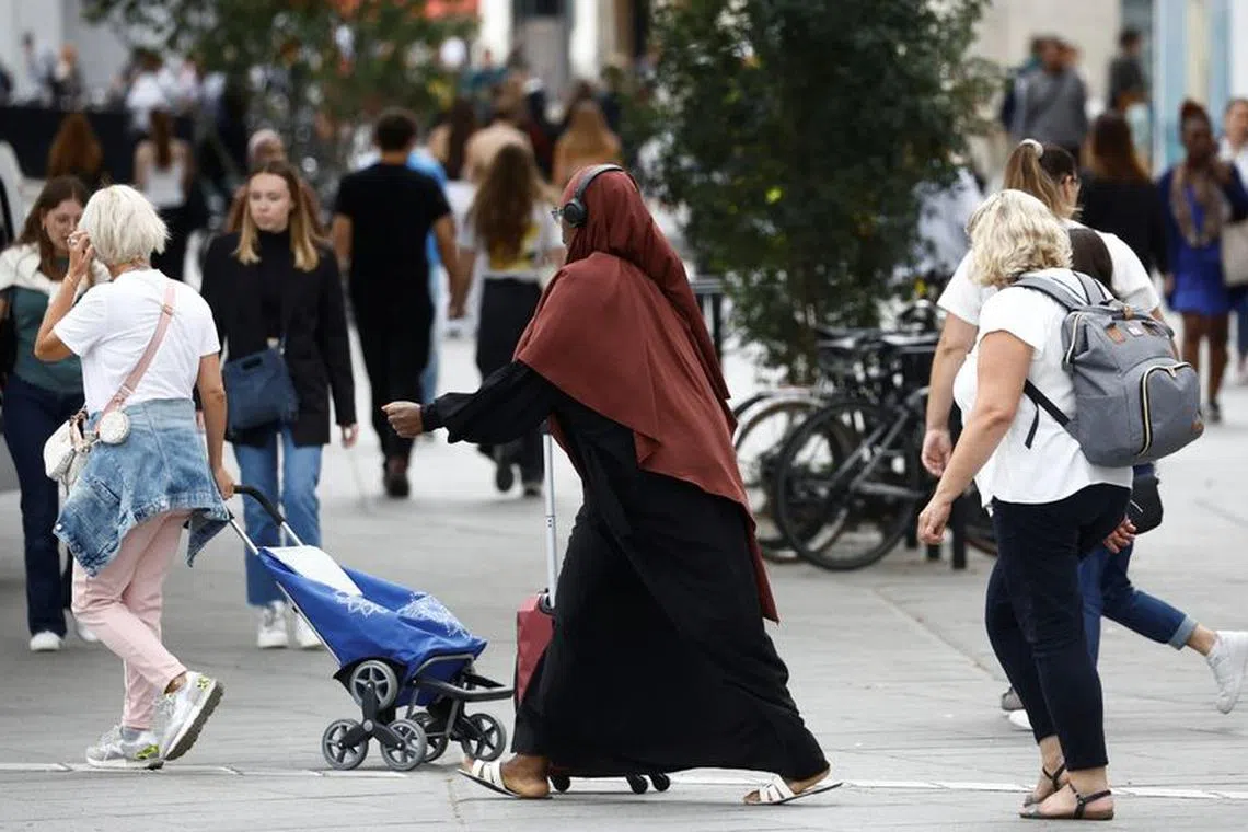 A Muslim woman, wearing the style of dress called an abaya, walks in a street in Nantes, France, August 29, 2023. REUTERS/Stephane Mahe/File Photo
