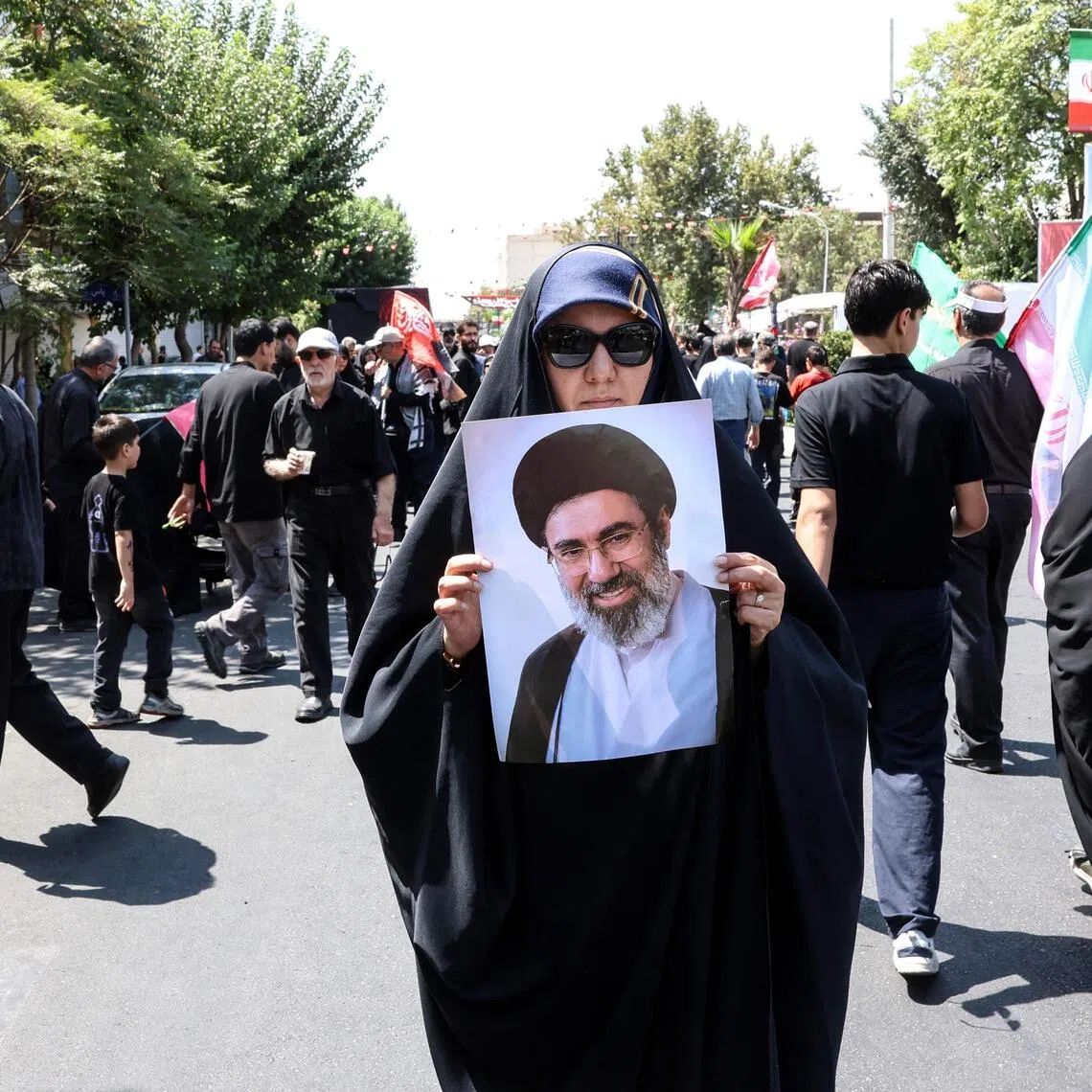 A woman holds a photo of Iran’s supreme leader Mojtaba Khamenei, who has not been seen in public since taking over Iran.