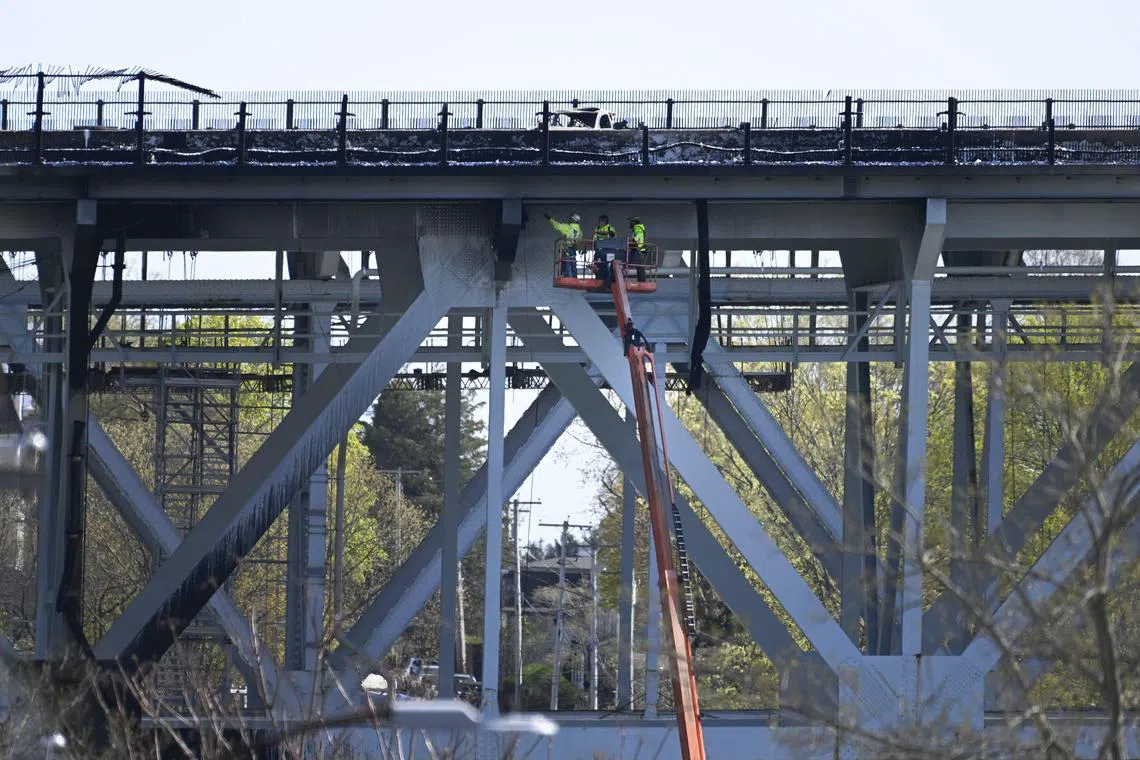 Workers inspect the Gold Star Memorial Bridge on Interstate 95 after a fuel tanker crashed and burned on the bridge in Groton, Conn., April 21, 2023. A massive explosion shut down part of Interstate 95 on Friday after a fuel tanker crashed on the bridge, sending a column of smoke and fire into the air and killing one person, state officials said. (Jessica Hill/The New York Times) 