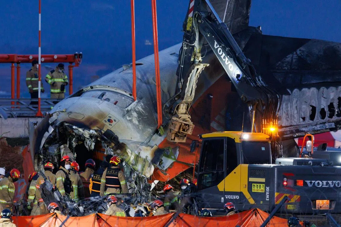 Resuce and inspection members in front of the wreckage of Jeju Air Co. Flight 2216 at Muan International Airport in Muan County, South Korea, on Sunday, Dec. 29, 2024. A Boeing Co. 737-800 aircraft operated by Jeju Air crashed and caught fire on an airport runway in South Korea, resulting in more than 170 people dead or missing. Photographer: SeongJoon Cho/Bloomberg