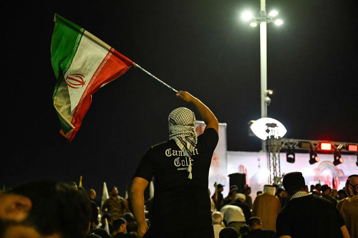 A demonstrator waves an Iranian flag, during a protest against Israel's attack on Iran, in Basra on June 13, 2025. (Photo by Hussein FALEH / AFP)