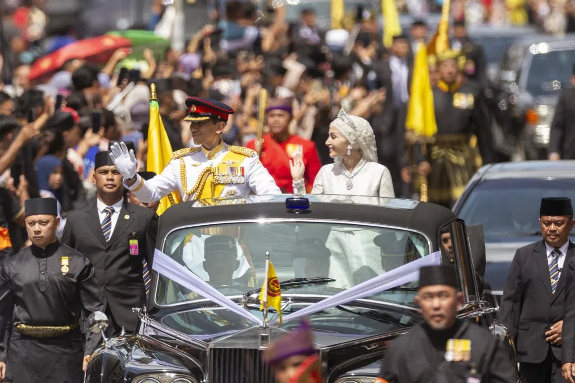 The newlywed royal couple Prince Abdul Mateen and his bride Anisha Rosnah greeting the crowd from a royal vehicle during the street procession of the royal wedding ceremony in Bandar Seri Begawan, Brunei, on Jan 14, 2024. 