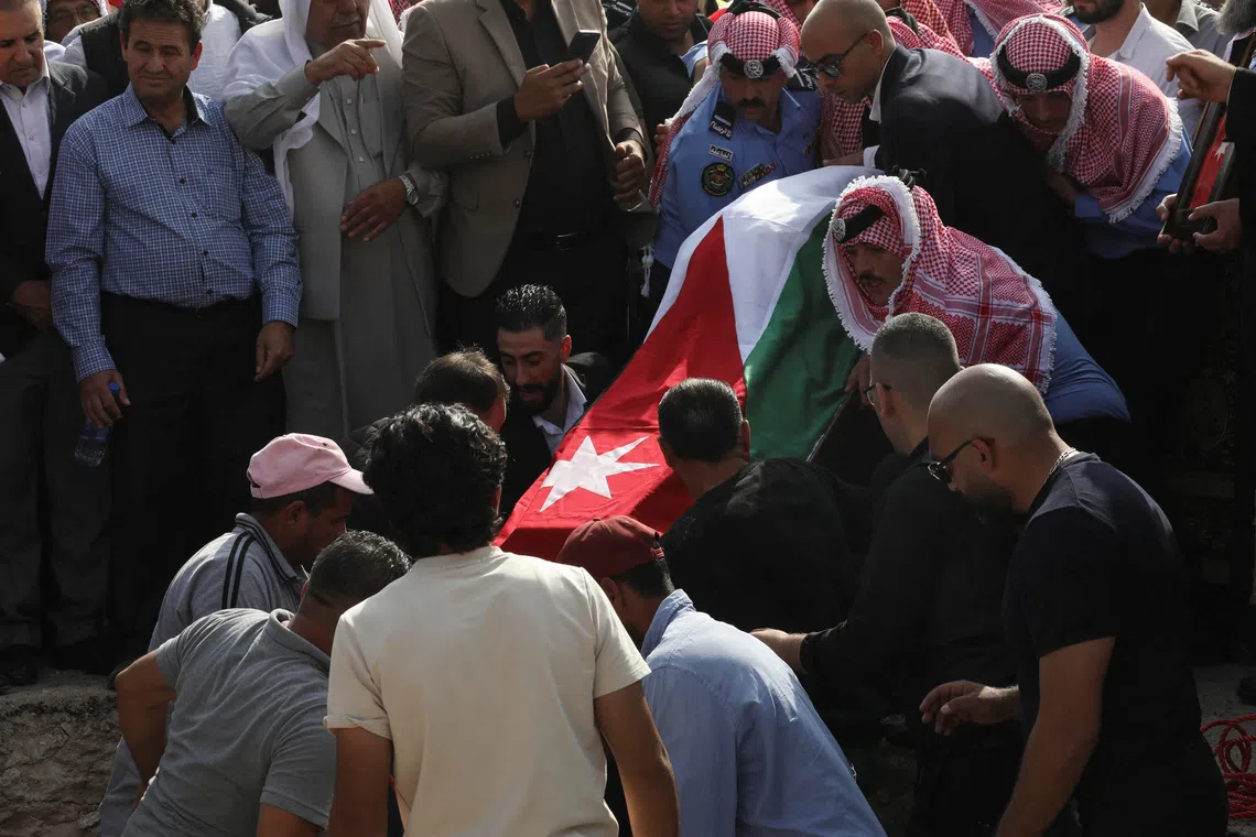 A coffin is lowered during the funeral for victims of a church shooting in Karak, Jordan, on Oct 25.