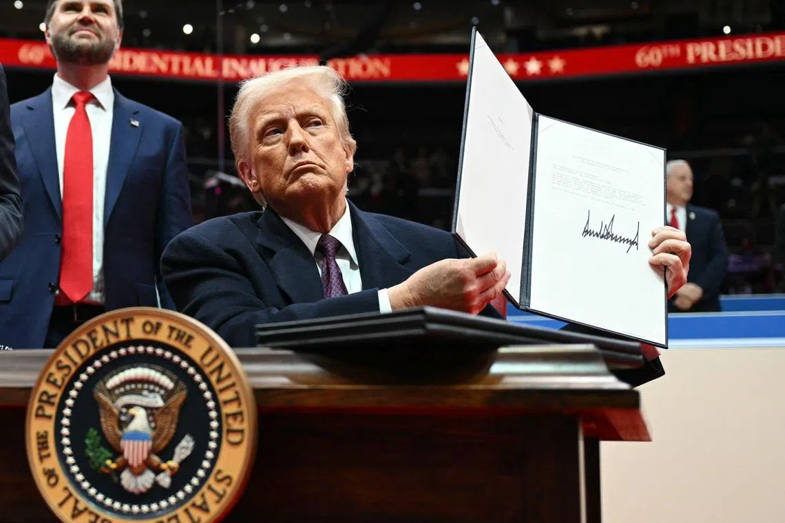 US President Donald Trump holds letter to the UN stating the US withdrawal from the Paris Agreement during the inaugural parade inside Capital One Arena, in Washington, DC, on January 20, 2025. (Photo by Jim WATSON / AFP)
