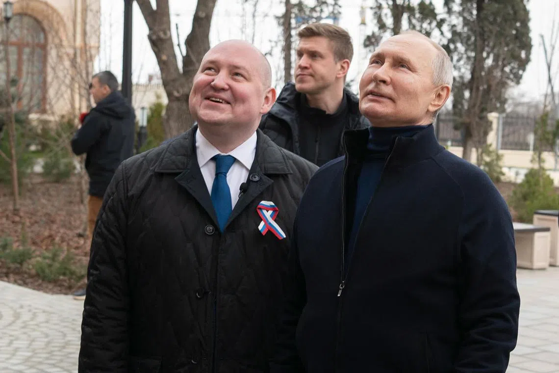 Sevastopol Governor Mikhail Razvozhayev (left) and Russian President Vladimir Putin visit a children's art and crafts centre in Sevastopol, Crimea, on March 18, 2023. 