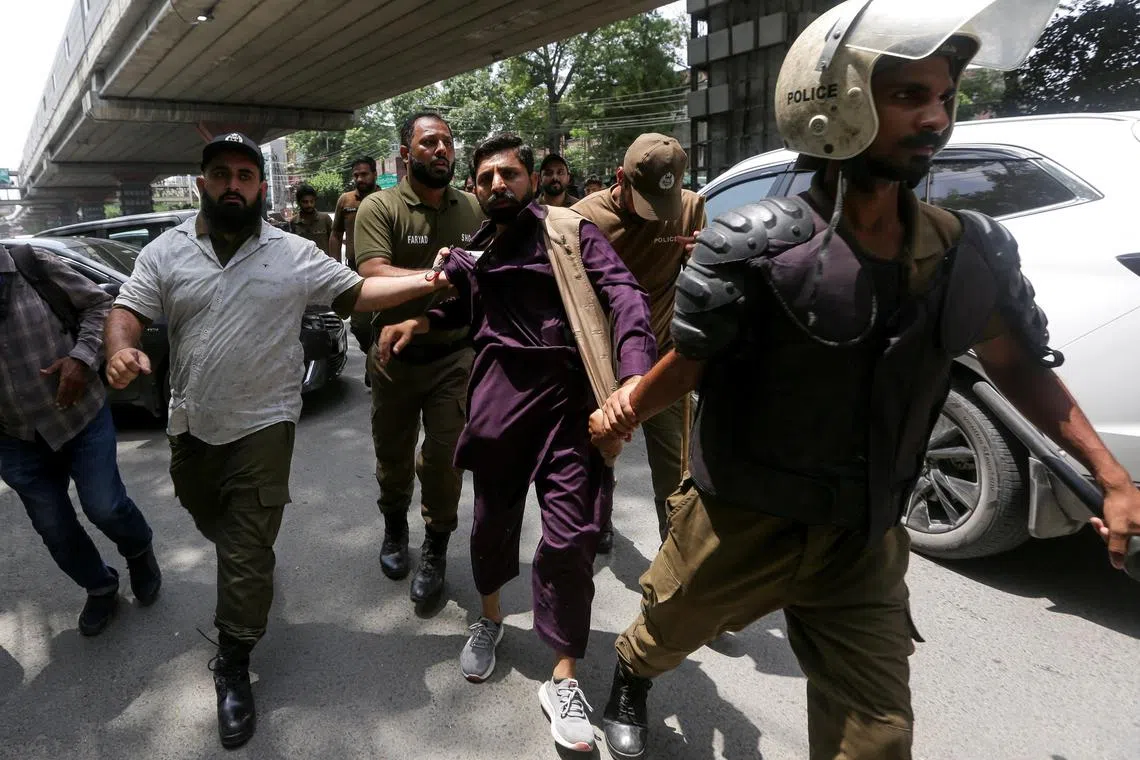 Police officers lead a detained supporter of Pakistan's former Prime Minister Imran Khan during a nationwide protest.