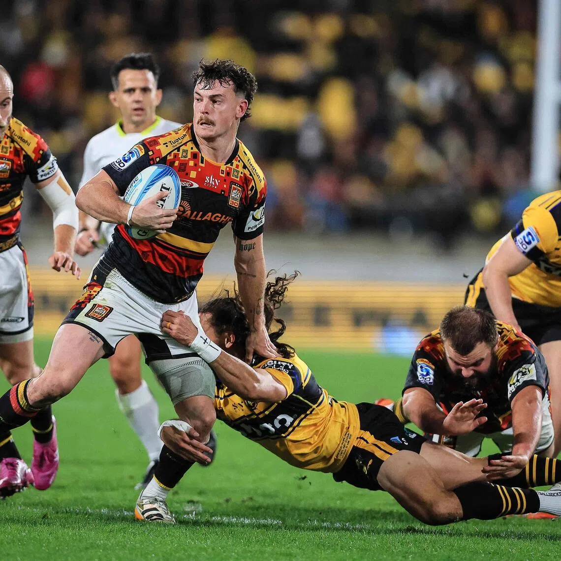 TOPSHOT - Chiefs Leroy Carter breaks the tackle of Hurricanes Ereatara Enari during the Super Rugby Pacific final match between the Wellington Hurricanes and Waikato Chiefs in Wellington on June 20, 2026. (Photo by Grant Down / AFP)
