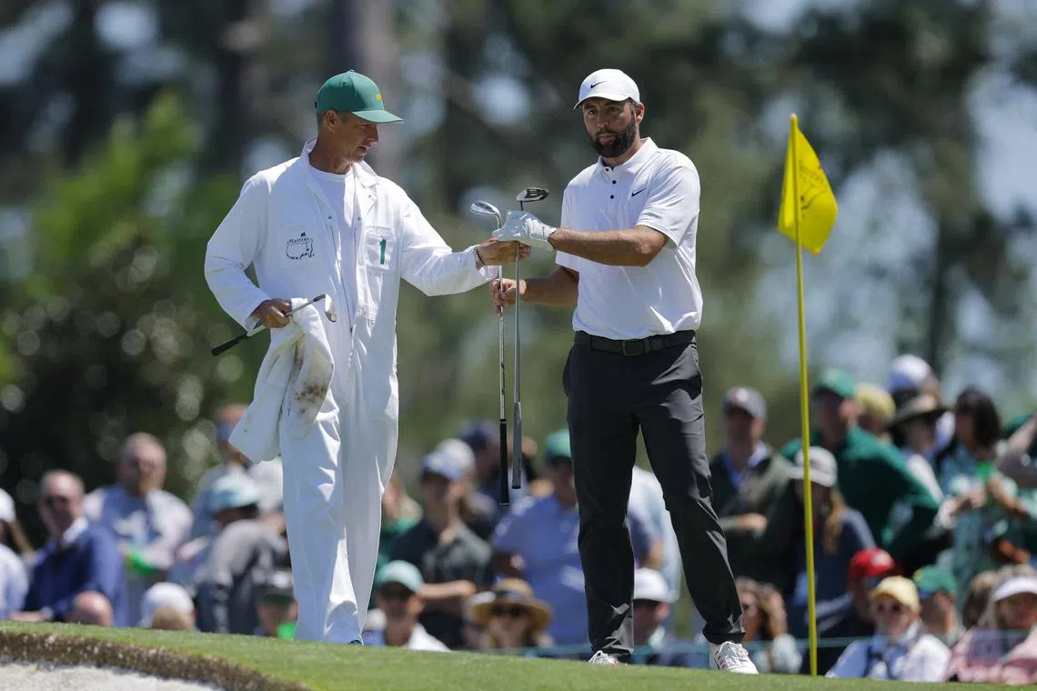 Golf - The Masters - Augusta National Golf Club, Augusta, Georgia, U.S. - April 8, 2025 Scottie Scheffler of the U.S. is given his putter by his caddie on the green on the 7th hole during a practice round REUTERS/Mike Blake