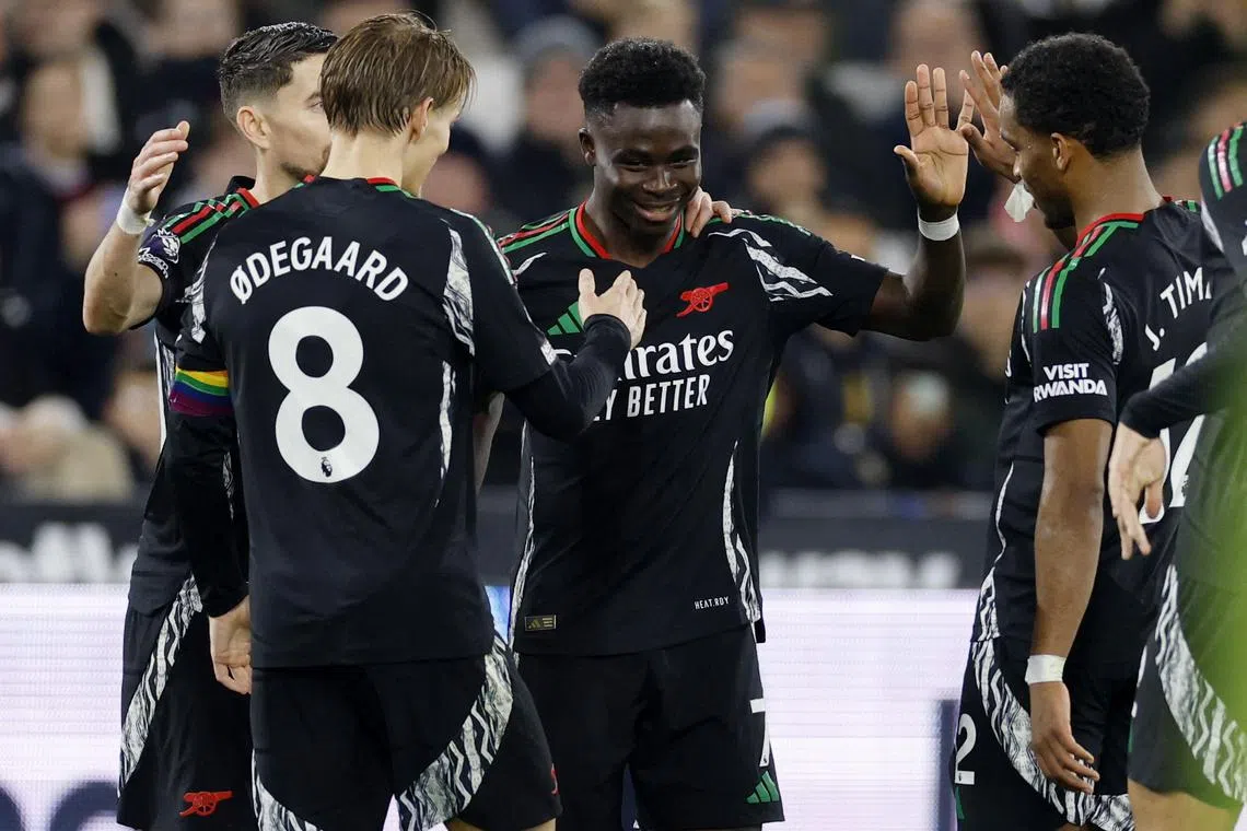 Arsenal's Bukayo Saka celebrates scoring their fifth goal with teammates Jurrien Timber and Martin Odegaard..