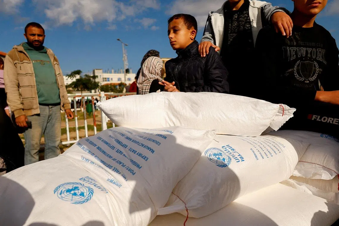 FILE PHOTO: Palestinians receive flour bags distributed by UNRWA in Rafah, in the southern Gaza Strip November 21, 2023. REUTERS/Ibraheem Abu Mustafa/File Photo