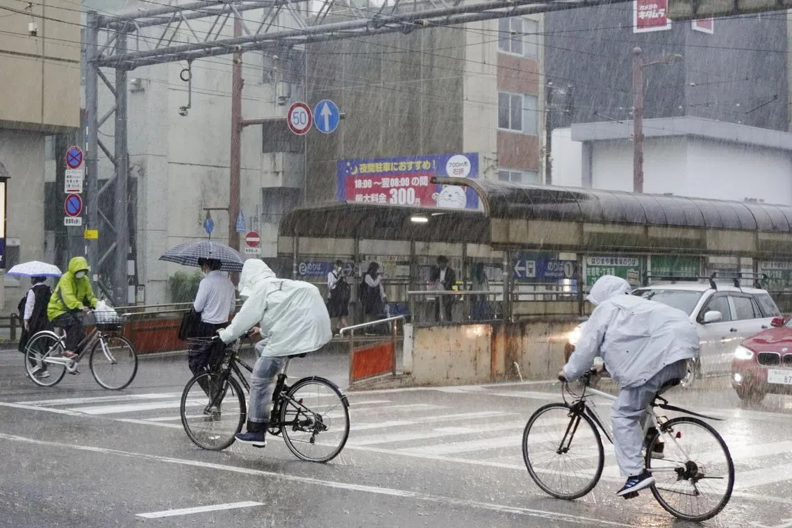 People riding bicycles make their way in the heavy rain in Kochi, Japan, on June 2.