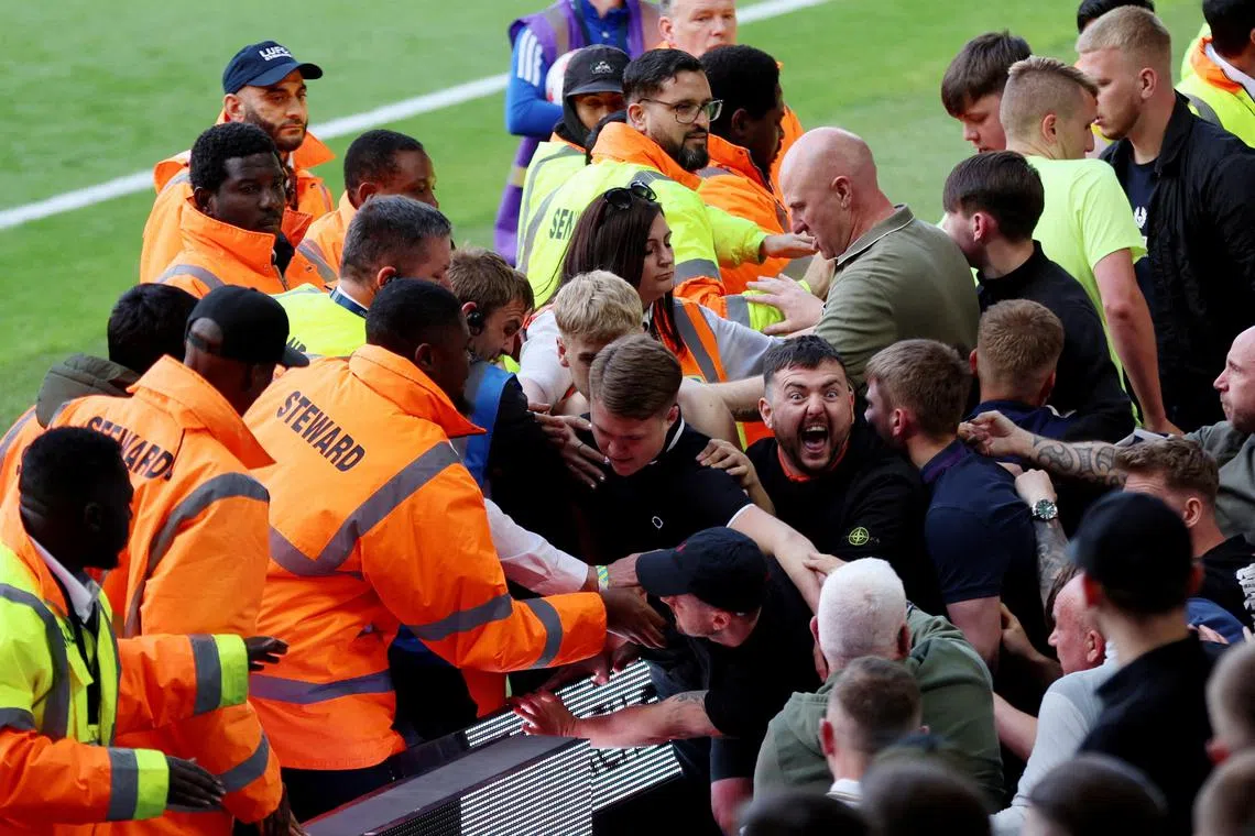Stewards trying to stop fans from invading the pitch after Leeds United are relegated from the Premier League on Sunday.