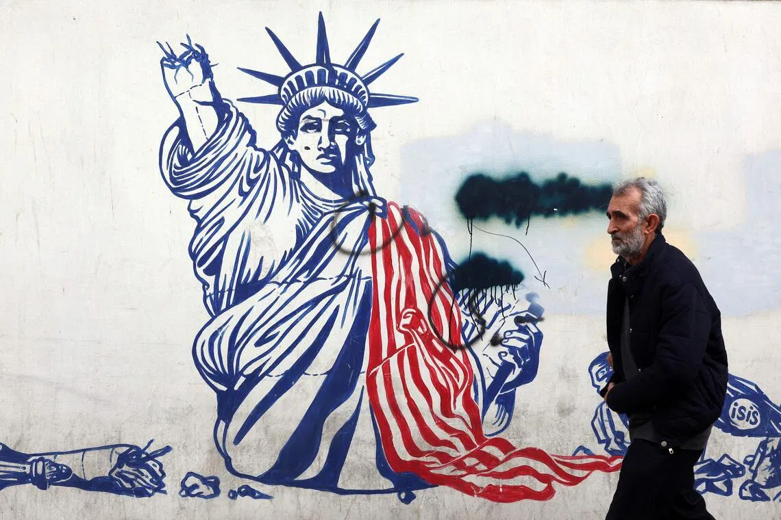 A man walks past a mural depicting the Statue of Liberty with is torch-bearing arm broken, painted on the outer walls of the former US embassy, in Tehran.