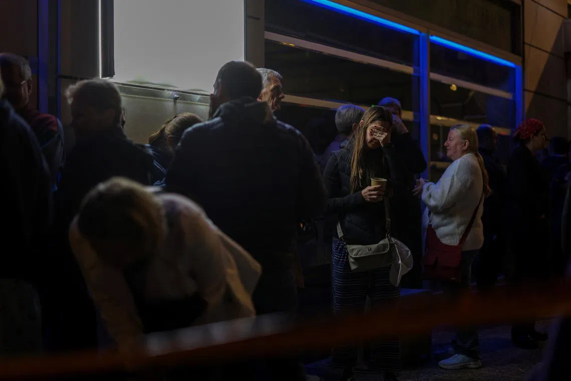 FILE PHOTO: A woman reacts as customers of a nearby hotel stand on the street following a bomb blast outside the Hellenic Train offices, in Athens, Greece, April 11, 2025. REUTERS/Stelios Misinas