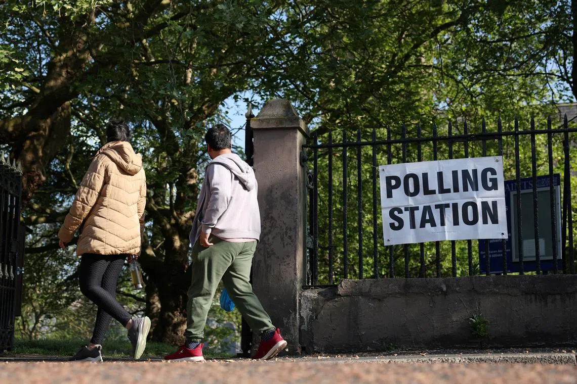 FILE PHOTO: People walk past a polling station sign outside a church as voting gets underway in the Runcorn and Helsby parliamentary by-election in Runcorn, Britain, May 1, 2025. REUTERS/Phil Noble/File Photo