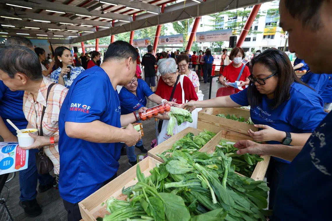 Beneficiaries receiving vegetables and fruits under the Neighbourhood Food Share programme at its Boon Lay distribution point on July 23. 