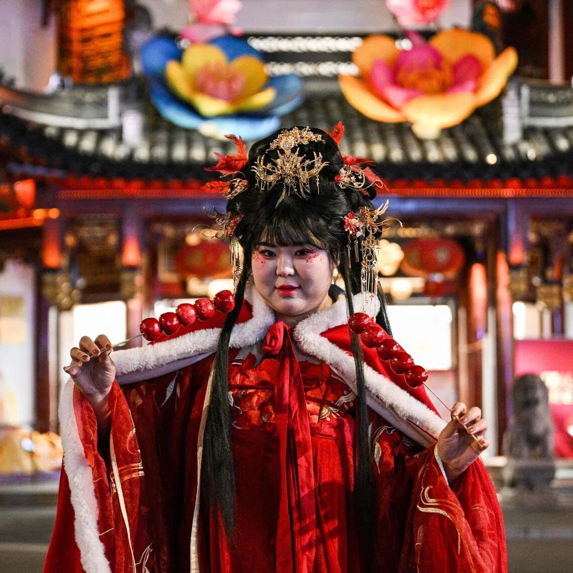 A woman wearing a traditional costume poses for a photograph on a street next to Yu Garden in Shanghai on January 21, 2026. (Photo by Hector RETAMAL / AFP)