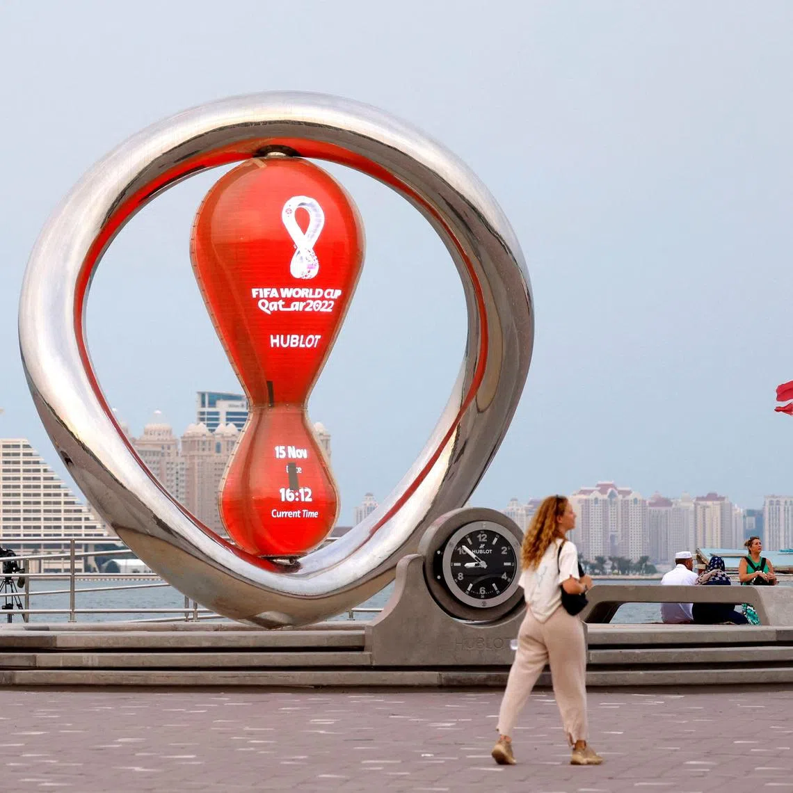 A picture taken on Nov 15, 2023 shows people walking past the 2022 World Cup countdown clock at the Corniche promenade in Doha. 