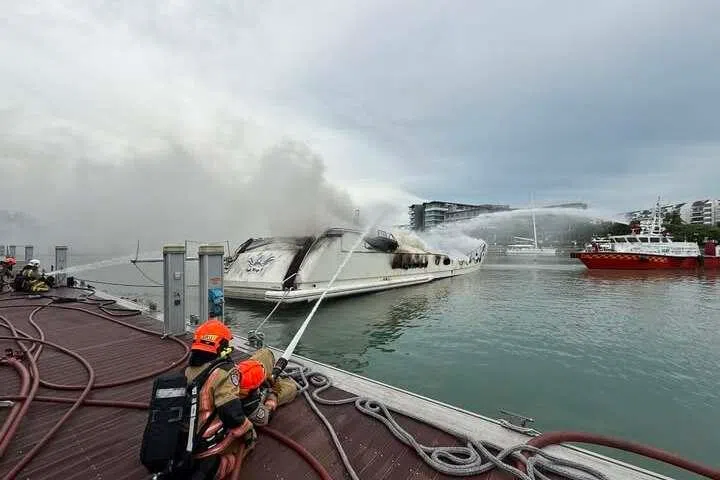 SCDF firefighters deploying a water jet from a pontoon at the ONE°15 Marina Club to fight a fire on a yacht on the morning of June 7.
