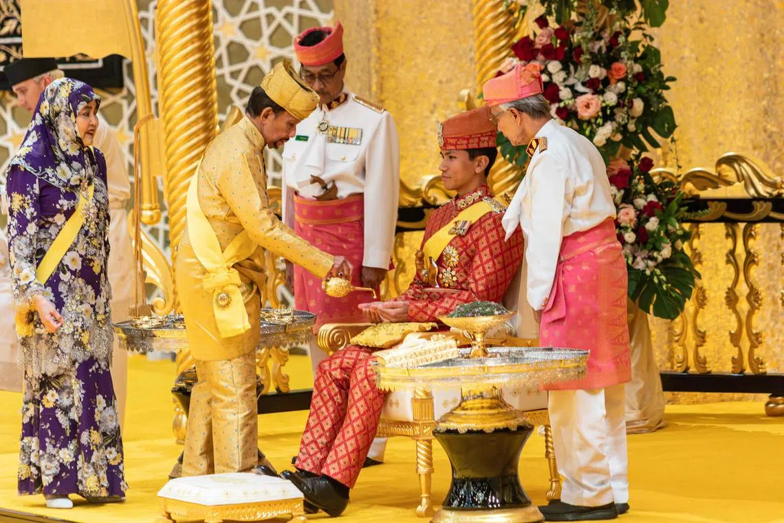 This photograph taken on January 10, 2024 shows Brunei's Sultan Hassanal Bolkiah (2nd L) pouring scented oil on the hands of Prince Abdul Mateen during the royal powdering ceremony at Istana Nurul Iman, ahead of his wedding to Anisha Rosnah, in Bandar Seri Begawan, as Queen Raja Isteri Pengiran Anak Hajah Saleha (L) looks on. 