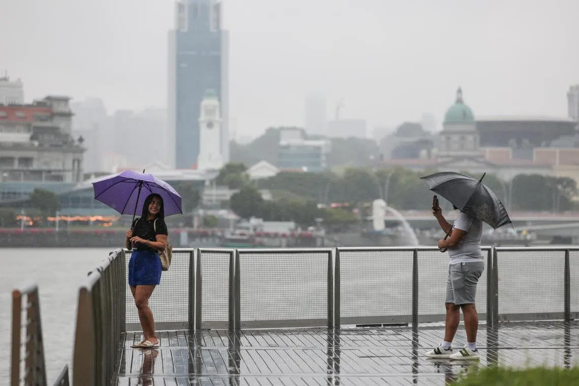 A tourist posing for a photo at Marina Bay Sands on a rainy, misty day, Jan 10, 2025.