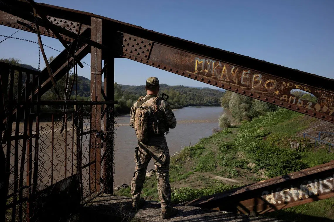 FILE PHOTO: A Ukrainian border guard surveys the border to Romania looking for people who cross illegally including men attempting to flee abroad to avoid military service, in Tyachiv, September 26, 2023.  REUTERS/Thomas Peter/File Photo