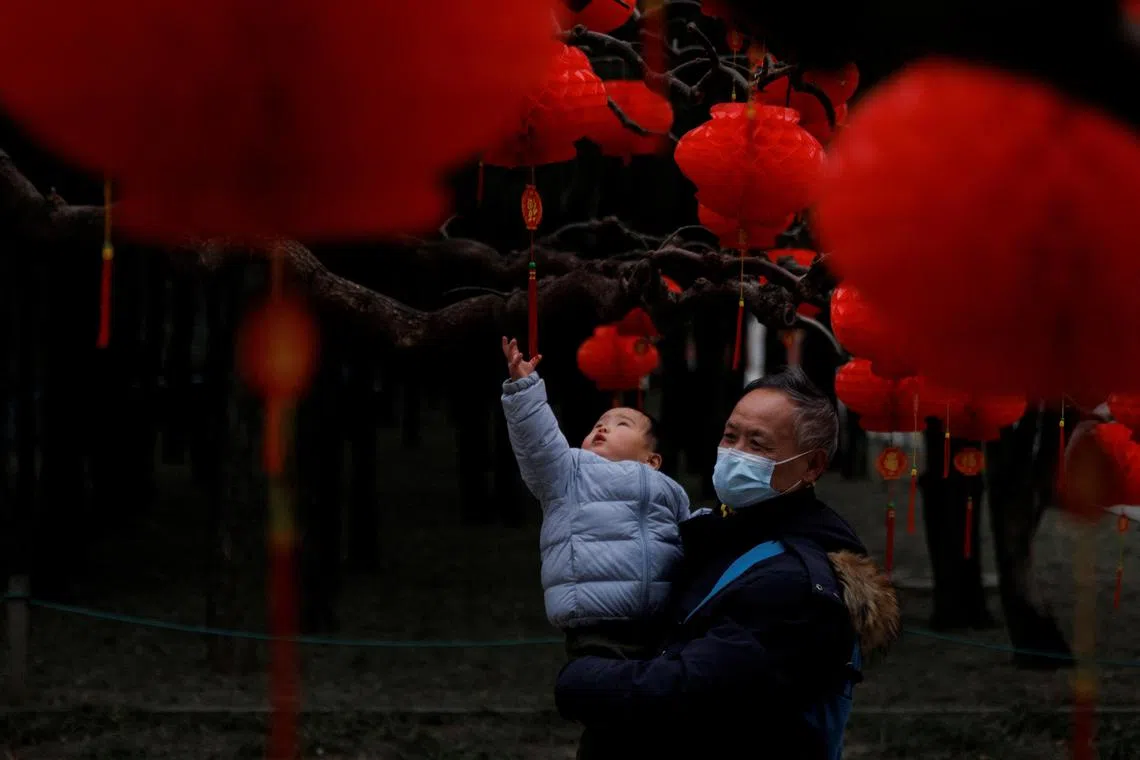 A child reaches for Spring Festival ornaments in a park ahead of Chinese Lunar New Year festivities in Beijing, China January 11, 2023. REUTERS/Thomas Peter     TPX IMAGES OF THE DAY     