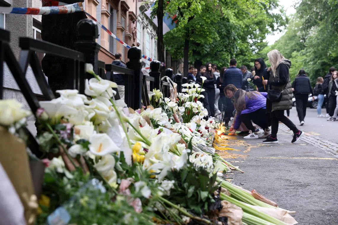 People leave flowers and light candles for the victims in front of the "Vladislav Ribnikar" elementary school in Belgrade, Serbia.