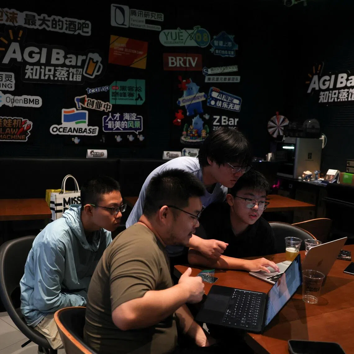 Song De, owner of AI-themed bar AGI Bar, discusses AI-related issues with customers at his AI-themed AGI Bar in Beijing.