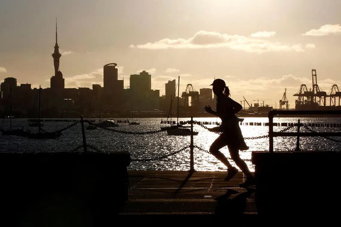 FILE PHOTO: A jogger runs along the seawall in Auckland September 26, 2011, with the city skyline in the background.  REUTERS/Stefan Wermuth/File Photo