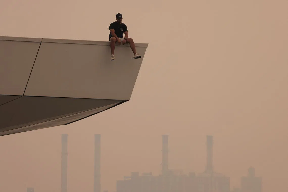 A person sitting on a lookout in Long Island City in Queens, as haze and smoke caused by wildfires in Canada blanket New York City, on June 7, 2023. 