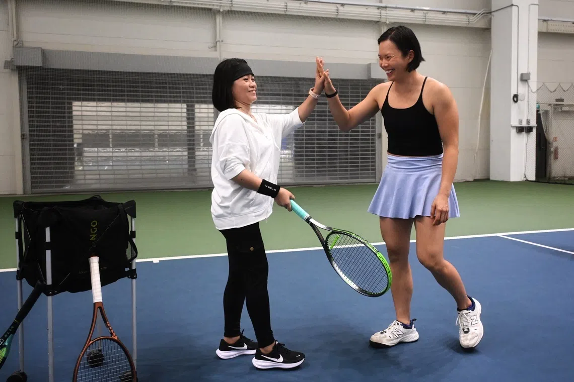 Singapore’s tennis player Sarah Pang (right) coaching Geraldine Humilde, from the Philippines at the tennis clinic for domestic helpers on Sept 21.