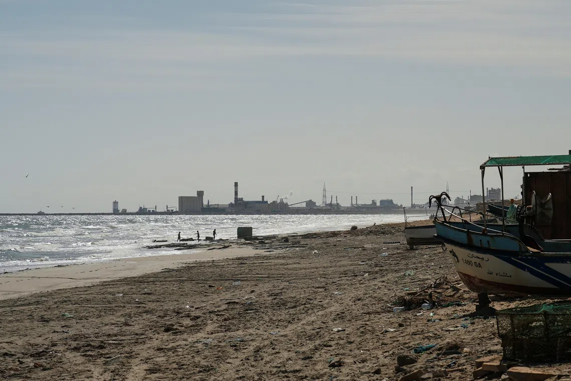 Children play on the beach with the Tunisian Chemical Group’s (CGT) phosphate complex visible in the background, in Gabes, Tunisia, October 16, 2025. REUTERS/Jihed Abidellaoui