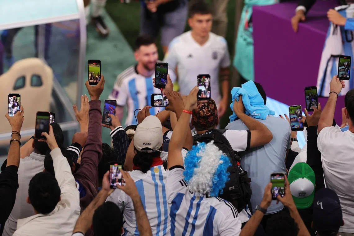 Argentina fans take pictures and videos of Lionel Messi as he leaves the pitch after the World Cup quarter-final match with the Netherlands.